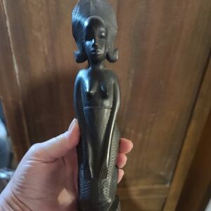 Carved wooden kneeling femalefigurine with elaborate headdress.